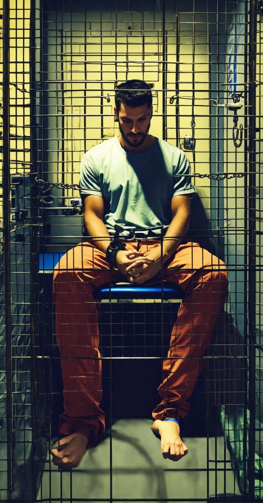 an individual placed in a prison cell with handcuf 3